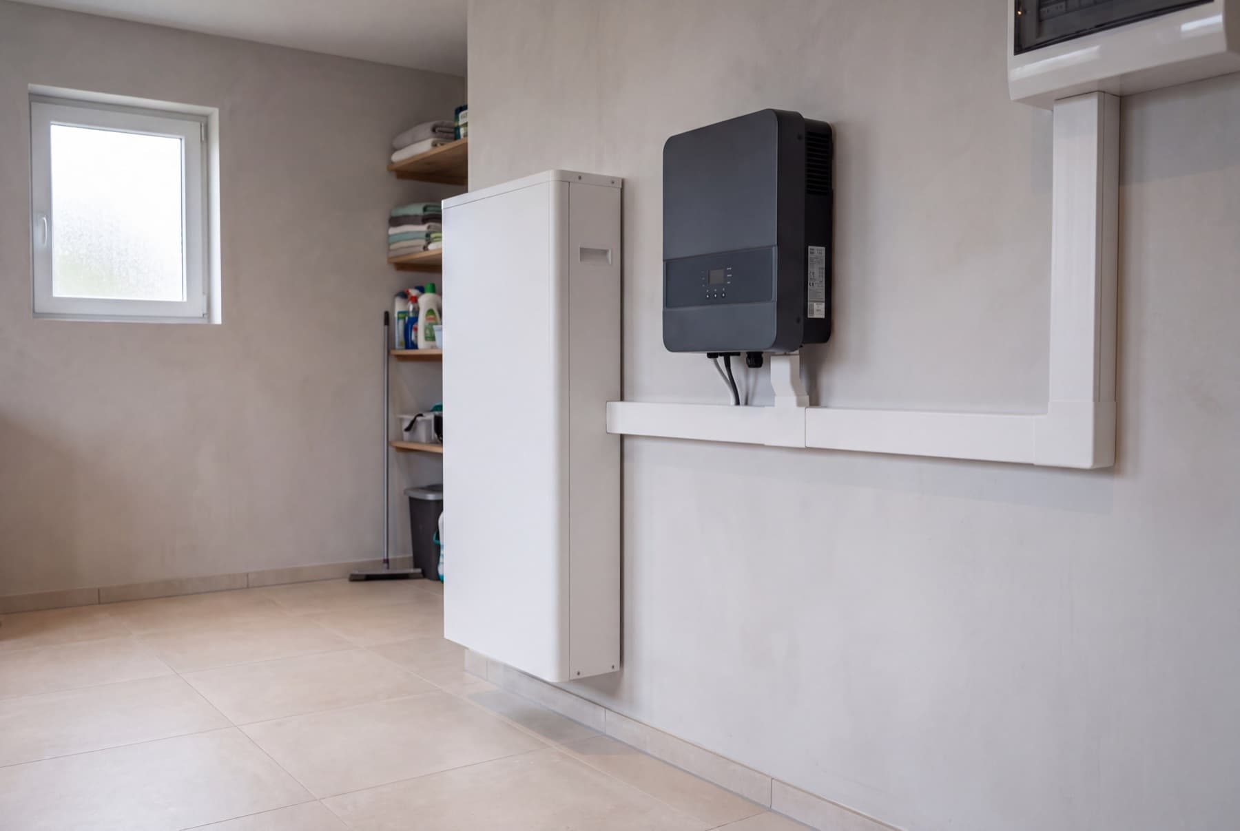 Elektricien monteert een thuisbatterij aan een bakstenen muur in een Nederlandse garage